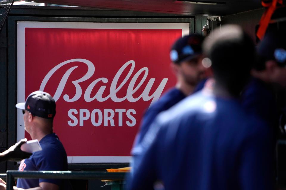 A Bally Sports sign hangs in the dugout before the start of a spring training baseball game between the St. Louis Cardinals and the Houston Astros in Jupiter, Fla.